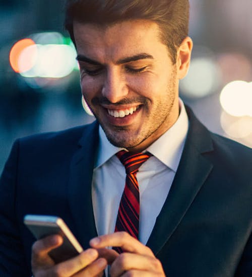 A man smiling while using his cellphone.